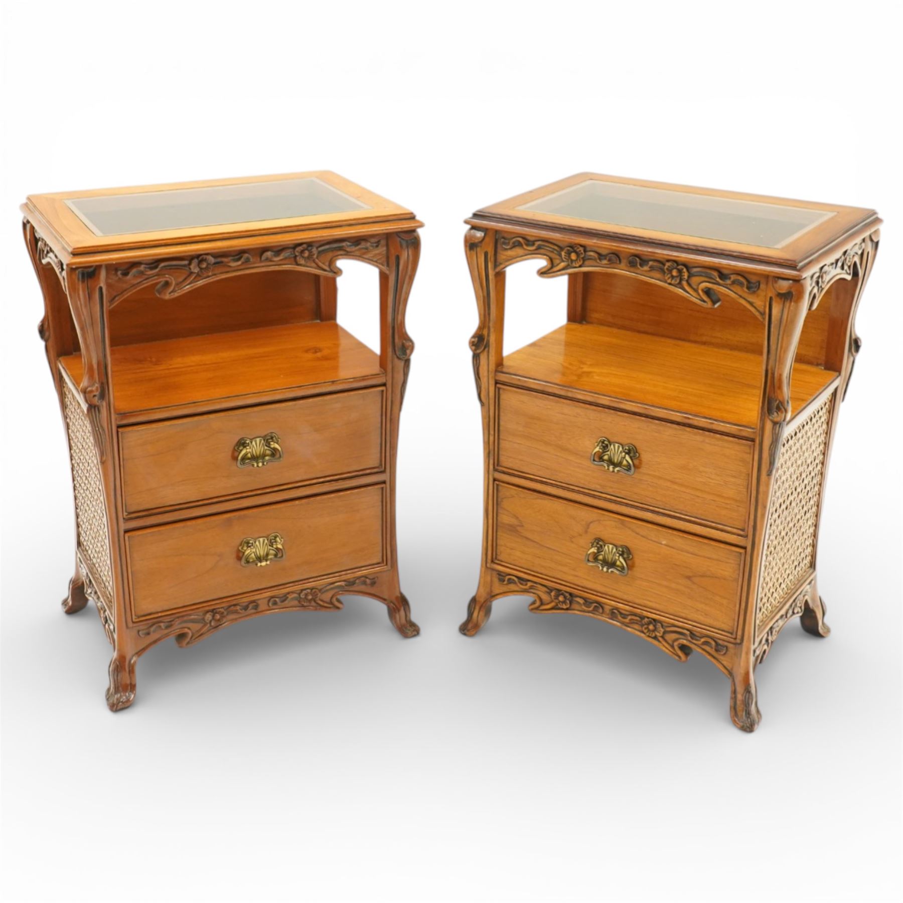 And So To Bed - pair of cherry wood and cane 'Libertine' bedside tables, glass top above a shaped and carved apron, with open recess above two drawers with brass handle, flanked by caned sides, raised on short cabriole supports 