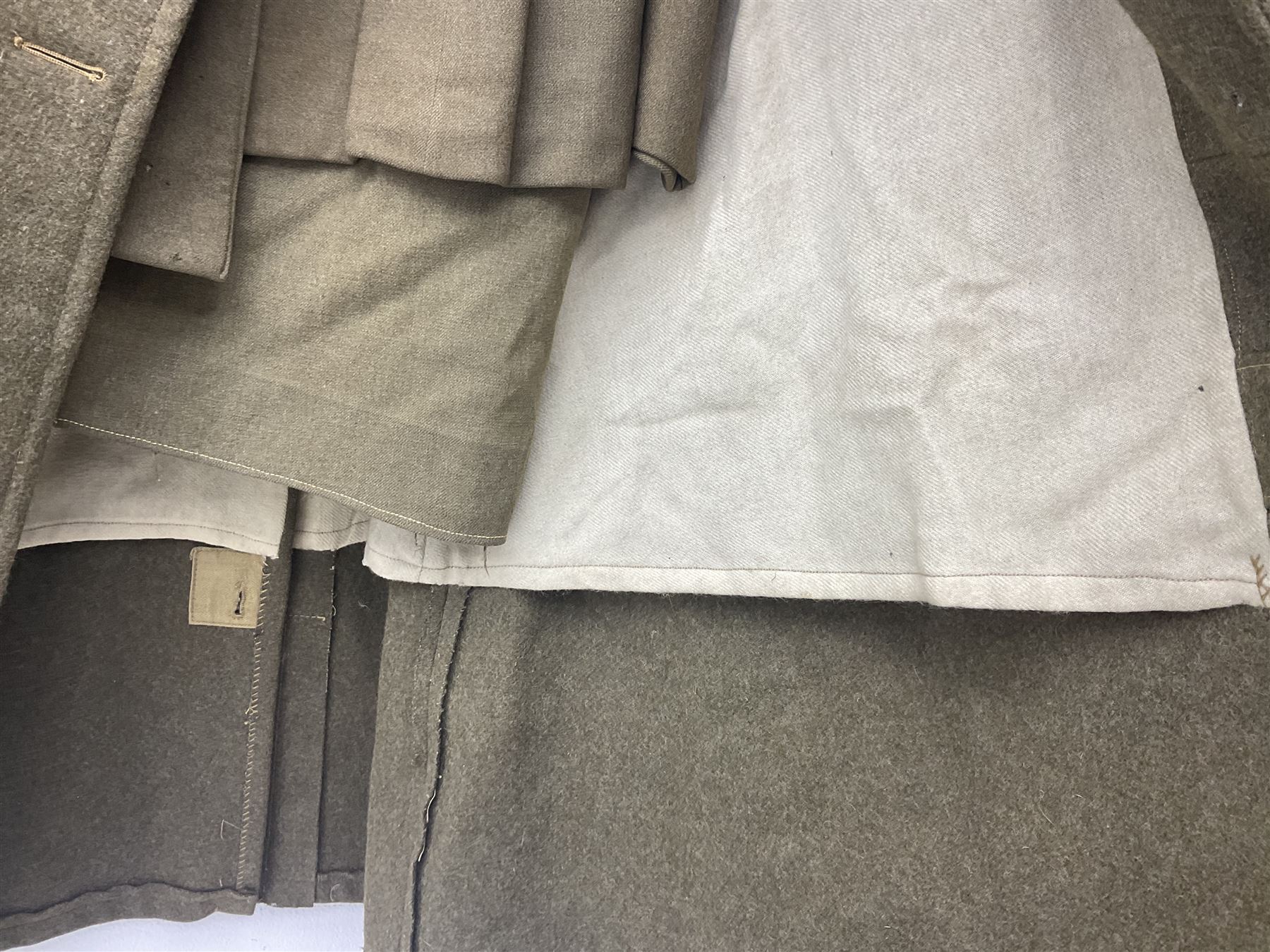 WW2 British female ATS Sergeant's service uniform grouping, consisting of four pocket female pattern service dress tunic with brass ATS shoulder titles and general service buttons; cloth lined interior with the original printed size label dated 1942; the matching khaki service dress skirt; and Greatcoat with size label dated 1945; together with army knitted sleeveless V-neck jumper; WRAC tunic, skirt and overcoat; full length cream and gold thread military evening dress by Hilliers Couture; and four webbing belts