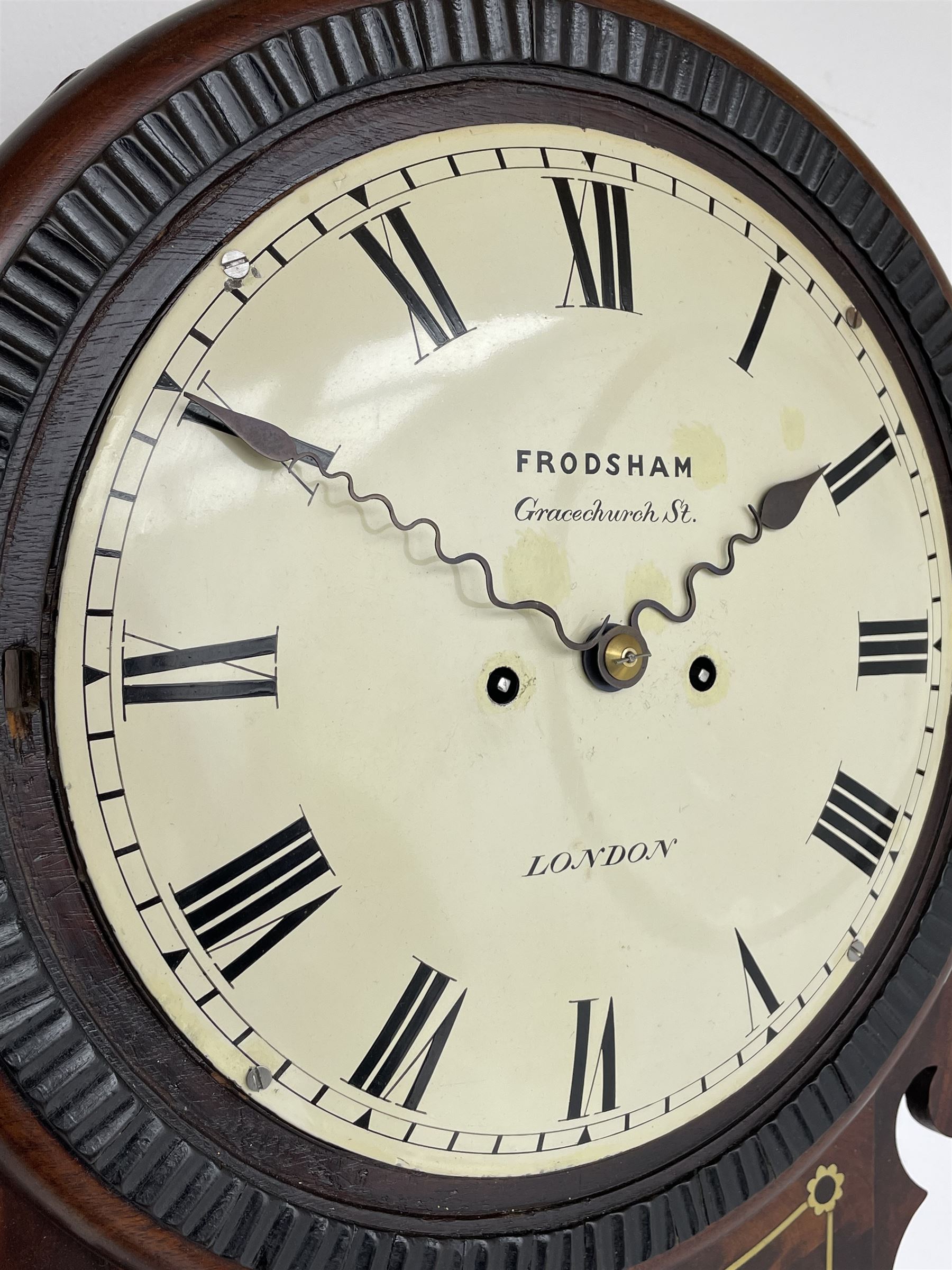 Frodsham of London - 8-day chain driven twin fusee wall clock in a mahogany case c1870, veneered case inlaid with brass stringing and motifs, shaped earpieces and chisel shaped base with pendulum adjustment door, 10” painted steel dial with Roman numerals, minute track and blued serpentine steel hands, dial inscribed Frodsham, Gracechurch Street, London, chain fusee, five-pillar, rack striking movement striking the hours on a cast bell. With pendulum.
H65 W34 D18
George Edward Frodsham, son of John Frodsham is recorded as working in Gracechurch Street, London 1869-79. Succeeded to Frodsham & Baker
