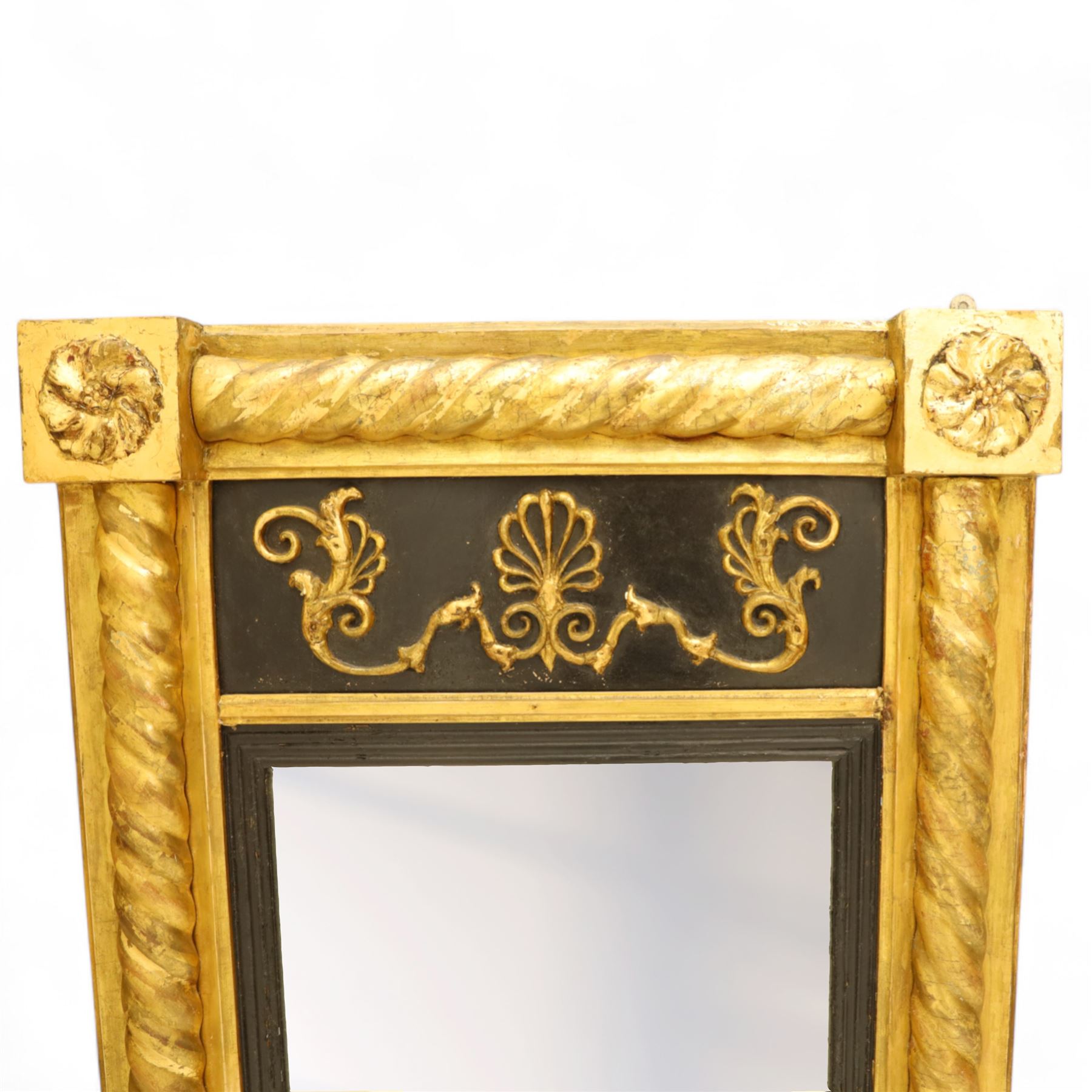 19th-century Regency-style ebonized and giltwood pier mirror, rectangular form frame with twisted rope columns on either side, ebonized frieze panel decorated with gilt applique scrollwork and central anthemion and arabesques