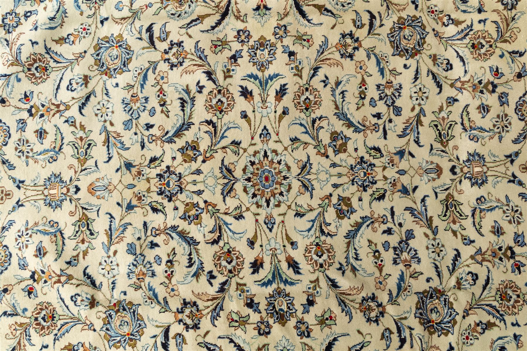 Central Persian Kashan hand-knotted rug, ivory field intricately decorated with an all-over design of scrolling vines, palmettes, and stylized lotus motifs in shades of soft blue, pale gold, and indigo within floral borders
