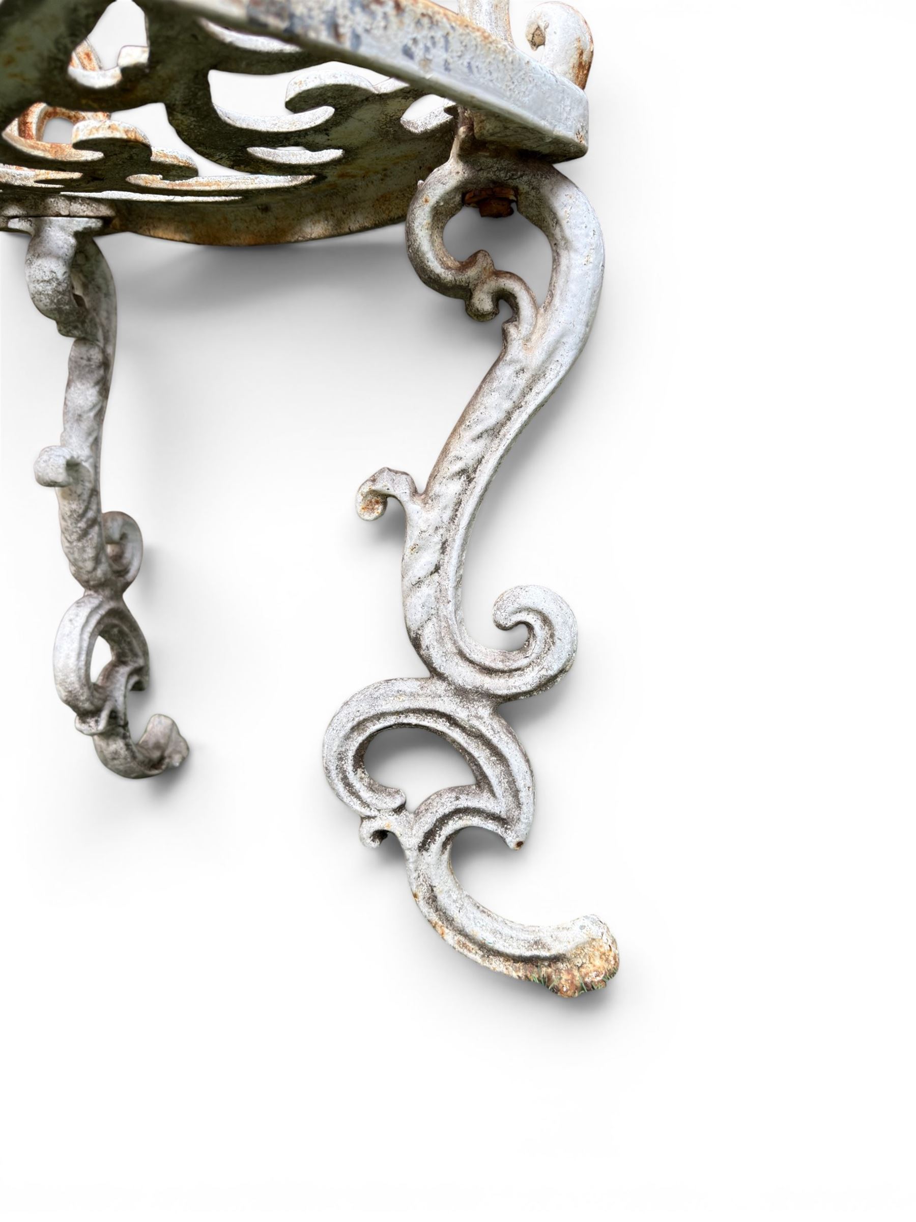 Pair of Victorian cast iron garden chairs, the ornate pierced back of scrolling foliate design, scrolling arm terminals over splayed supports formed of C and S-scrolls, in distressed white painted finish