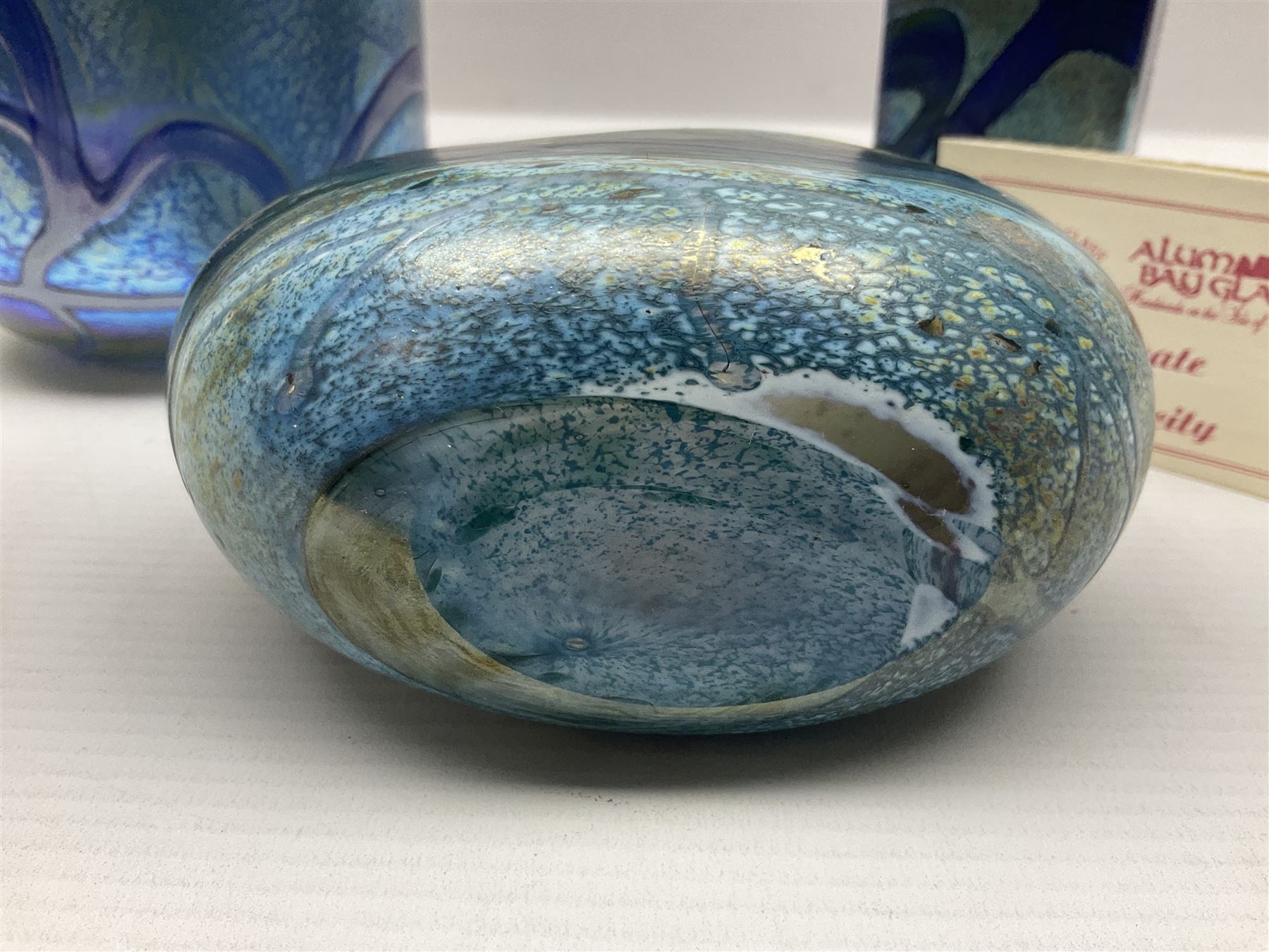 Two Isle of White glass vases, by Alum Bay Glass, both with blue swirl design upon an iridescent mottled blue/green ground, together with a Gozo Glass vase of pebble form, with similar design, H12cm