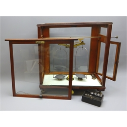  Set of brass Scientific balance Scales stamped  L.Oertling, London E.C. with a part set of Griffin & Tatlock weights, in glazed mahogany case with sliding front and hinged side doors on three adjustable brass feet, W46cm, H50cm, D23cm  