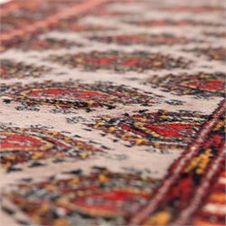 Tekke Bokhara hand knotted  runner, crimson field decorated with a series of repeating Tekke gul motifs arranged in rows within narrow geometric borders with chevron and diamond devices, 78x248cm 
