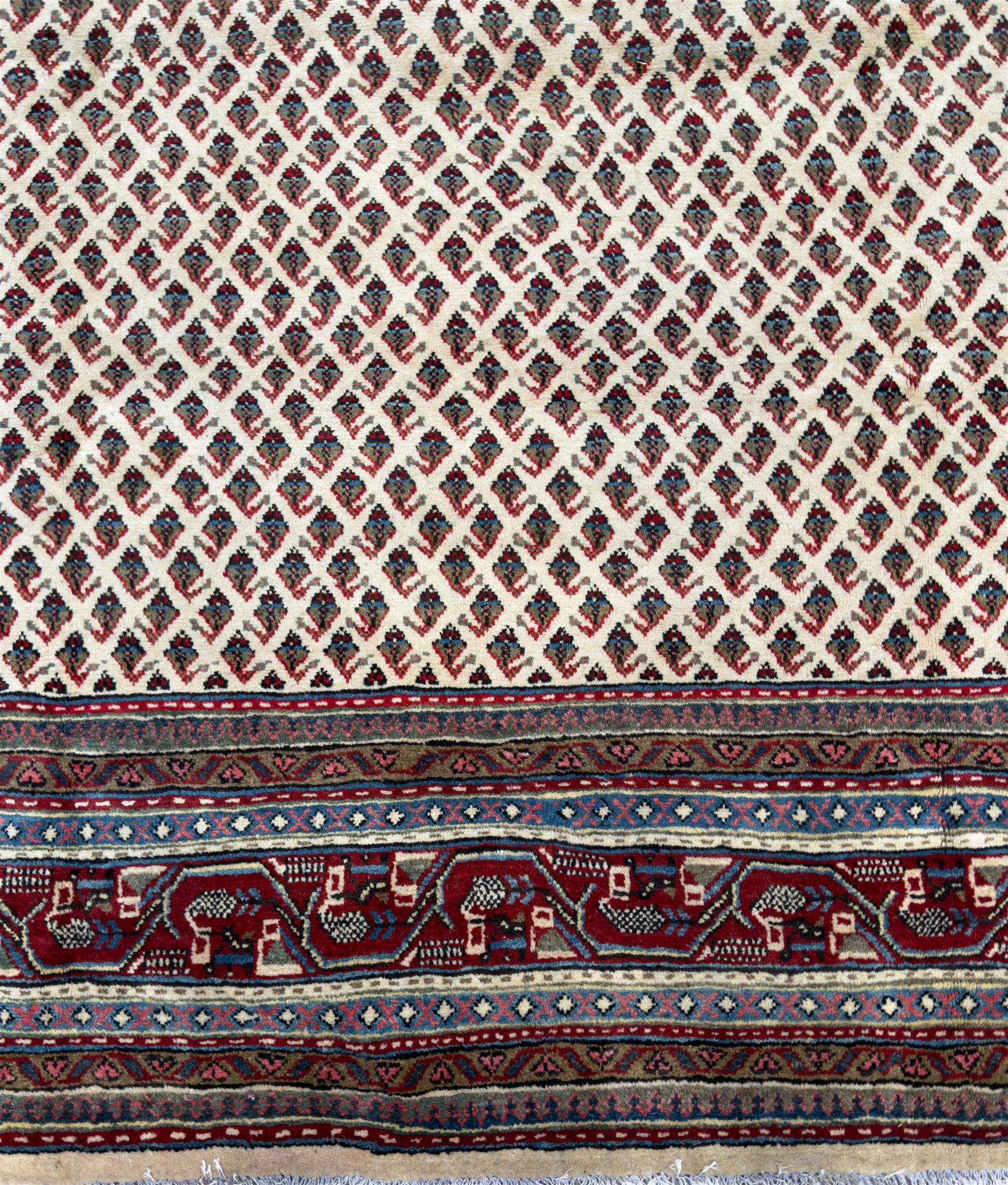 Northwestern Persian Bottehmir hand-knotted rug, ivory field with an all-over design of boteh motifs arranged in diagonal rows within multiple borders and a primary madder red field with stylized vine and flowerhead motifs, 320cm x 214cm 