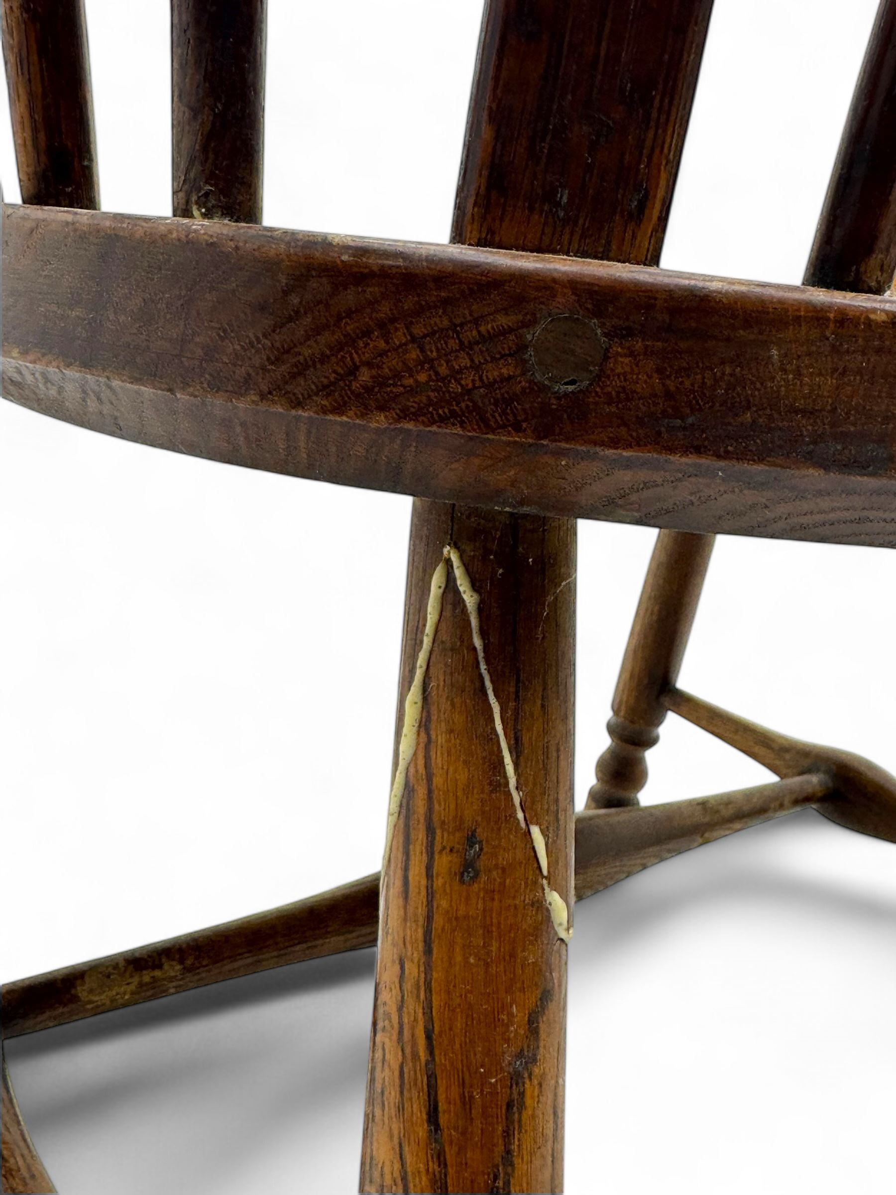 Early-to-mid 19th century elm and ash high-back Windsor armchair, central vase-shaped splat flanked by slender vertical spindles, outward-curving arms, shaped and dished saddle seat, raised on turned and splayed supports united by H-stretcher