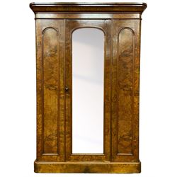 Victorian walnut wardrobe, projecting cavetto cornice over banded frieze, fitted with central door with arched bevelled mirror plate flanked by arch panels with moulded slips, enclosing brass hanging rail and hooks