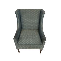 Early 20th century high wing-back armchair, upholstered in pale teal lozenge patterned fabric, raised on turned and fluted supports