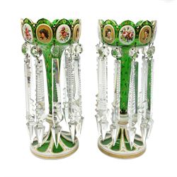 Pair of 19th century Bohemian green glass lustres, the castellated bowls decorated with overlaid panels of flowers and female portraits, upon tapering stems and overlaid spreading feet, heightened throughout with gilt, each supporting ten prismatic drops, H35cm