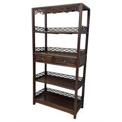 Early 20th century Chinese hardwood display étagère bookcase, the rectangular open tiered frame with pierced frieze and geometric openwork gallery to each shelf, fitted with two short drawers carved with stylised lotus motifs, supported on square uprights with pierced apron and integral gallery rails