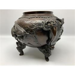 Japanese bronzed koro, the body of globular form with twin cast zoomorphic mask handles, decorated in relief with birds upon blossoming branches, against a ground incised with rushes and peonies, the flat toped domed cover with pierced band and surmounted by a cast figure of a Foo dog, the whole upon three zoomorphic mask feet, with impressed character type mark beneath, H35.5cm