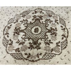 Cream ground woollen rug, thick shaggy pile, central shaped medallion with curled stylised foliate decoration 