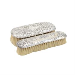 Group of silver mounted dressing table items, to include dwarf candlestick, with embossed ribbon decoration, comb holder, jar lid and six clothes brushes, all hallmarked 