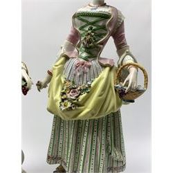 Pair of large 19th century Jacob Petit figures, in the style of Meissen's Gardener and companion, each modelled in 18th century dress and holding posy in the one hand and basket of flowers in the other, upon circular floral encrusted bases, each with spurious blue crossed sword marks beneath, the male figure also marked with blue underglaze mark 'JP', tallest H46cm