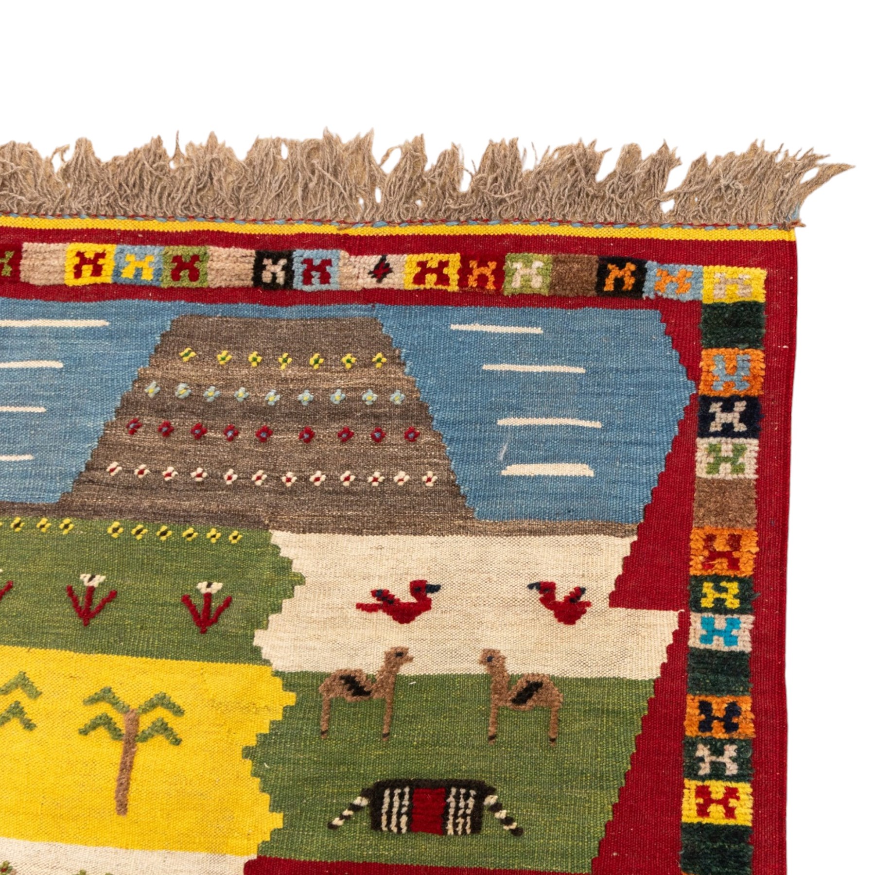 South West Persian Qashqai kilim, the field arranged with stepped polychrome panels depicting stylised camels, goats, cattle and birds, interspersed with trees and flowering stems, enclosed by a red border with multicoloured geometric devices