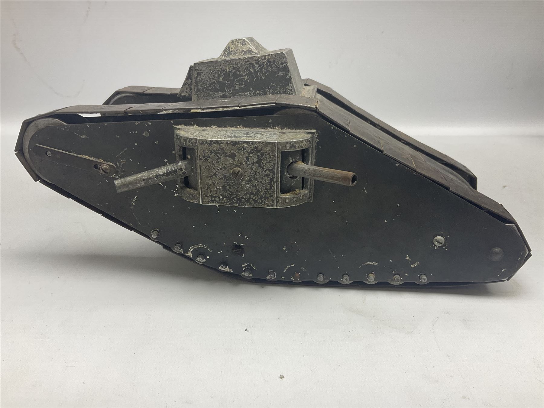 Large clockwork model of a WW1 Tank made of tin-plate and aluminium, with moving side cannons, the clockwork chain driven movement driving the articulated tin tracks; L28.5cms  W16.5cms and H13.5cms
