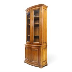 Wesley Barrell - French cherry wood bow front display cabinet, the upper section with glazed doors and three adjustable shelves, raised on cupboard base with brushing slide and further adjustable shelf, raised on a moulded plinth base with bracket feet