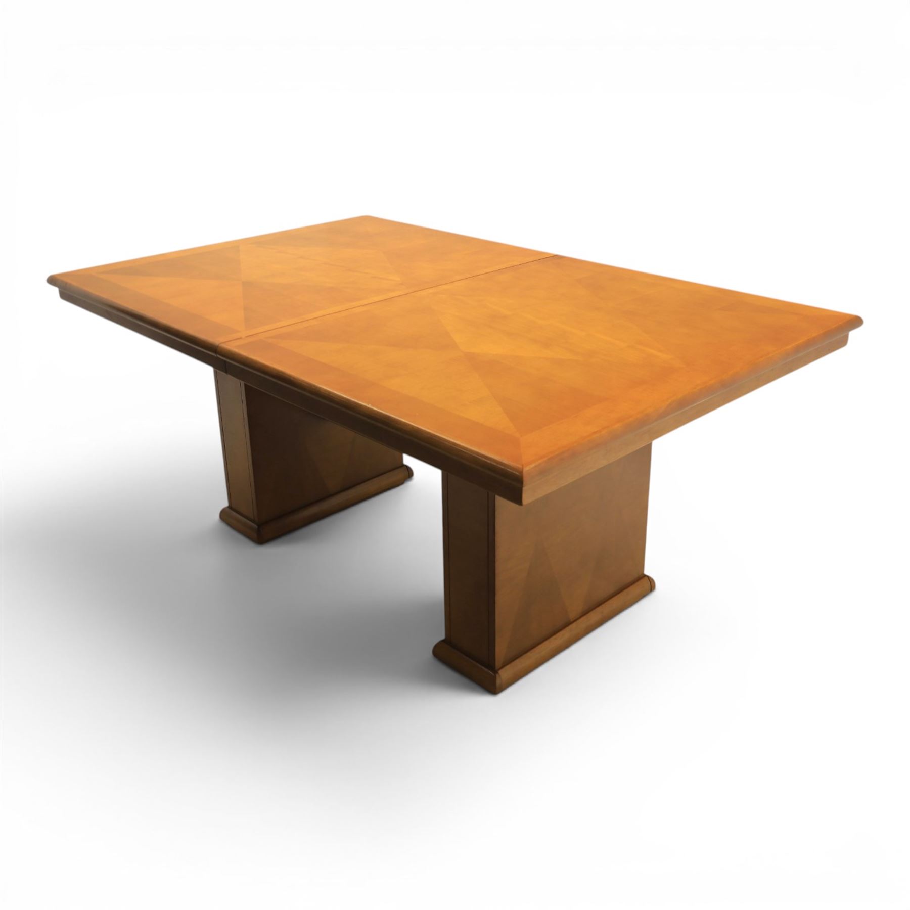 Modern Art Deco design walnut extending dining table, rectangular top with rounded moulded edge, geometric parquetry veneered panels, extending action with additional leaf extending to 220cm, on twin panelled pedestal supports with stepped plinth feet