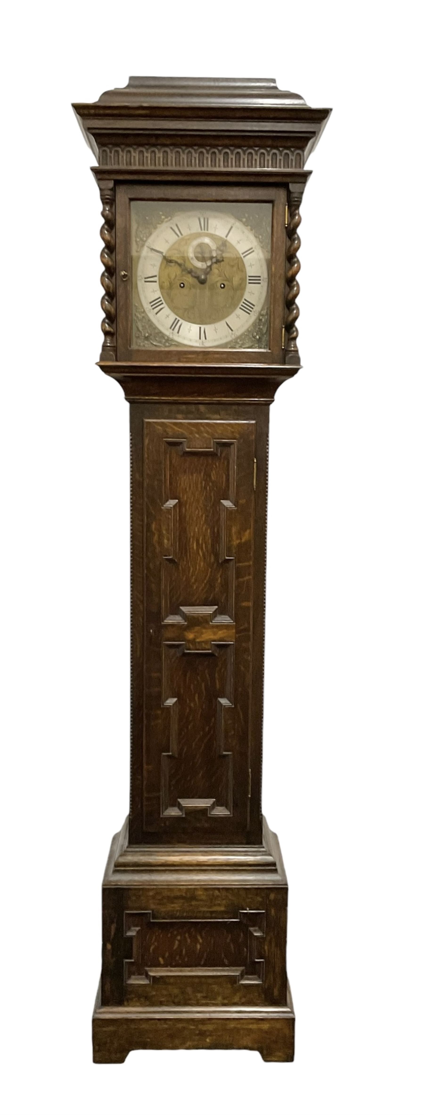 8-day oak longcase clock - in an early 18th century styled case with a caddy top, square hood door with barley twist columns, long carved trunk door on a conforming plinth with an applied skirting base, square brass dial with an engraved centre, silvered chapter and spandrels, 19th century rack striking movement, striking the hours on a bell. With weights and pendulum.