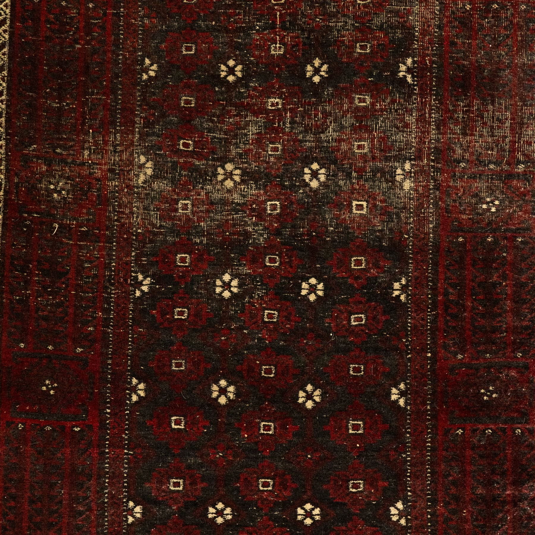 Three rugs,  comprising a Baluch rug in crimson ground, 179x97cm, a Tekke Bokhara rug in crimson ground, 201x132cm, and a Bokhara rug in ochre ground, 125x175cm 