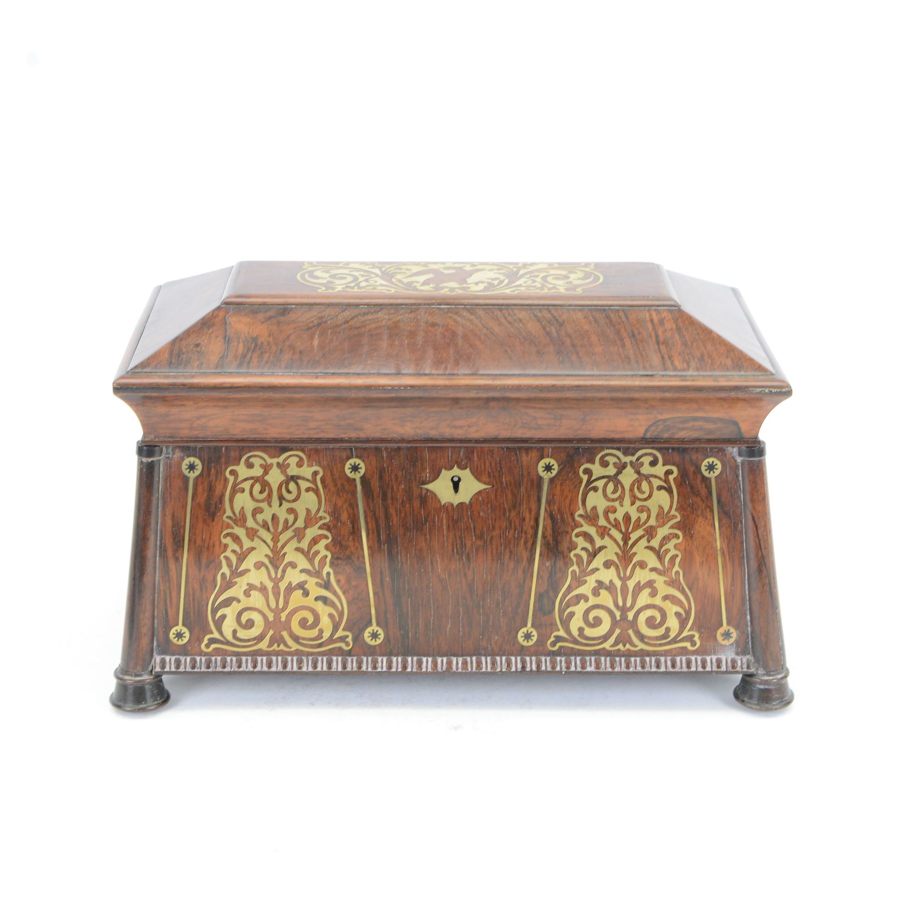 Early 19th century rosewood and brass inlaid tea caddy, of sarcophagus form, the front and hinged opening cover inlaid with brass scrolling panels, opening to reveal a compartmented interior with twin removable boxes with conforming inlaid brass detail to the hinged covers and zinc lining to the interiors, flanking a later glass mixing bowl, the whole upon four turned cylindrical feet, H21cm W36cm D20cm