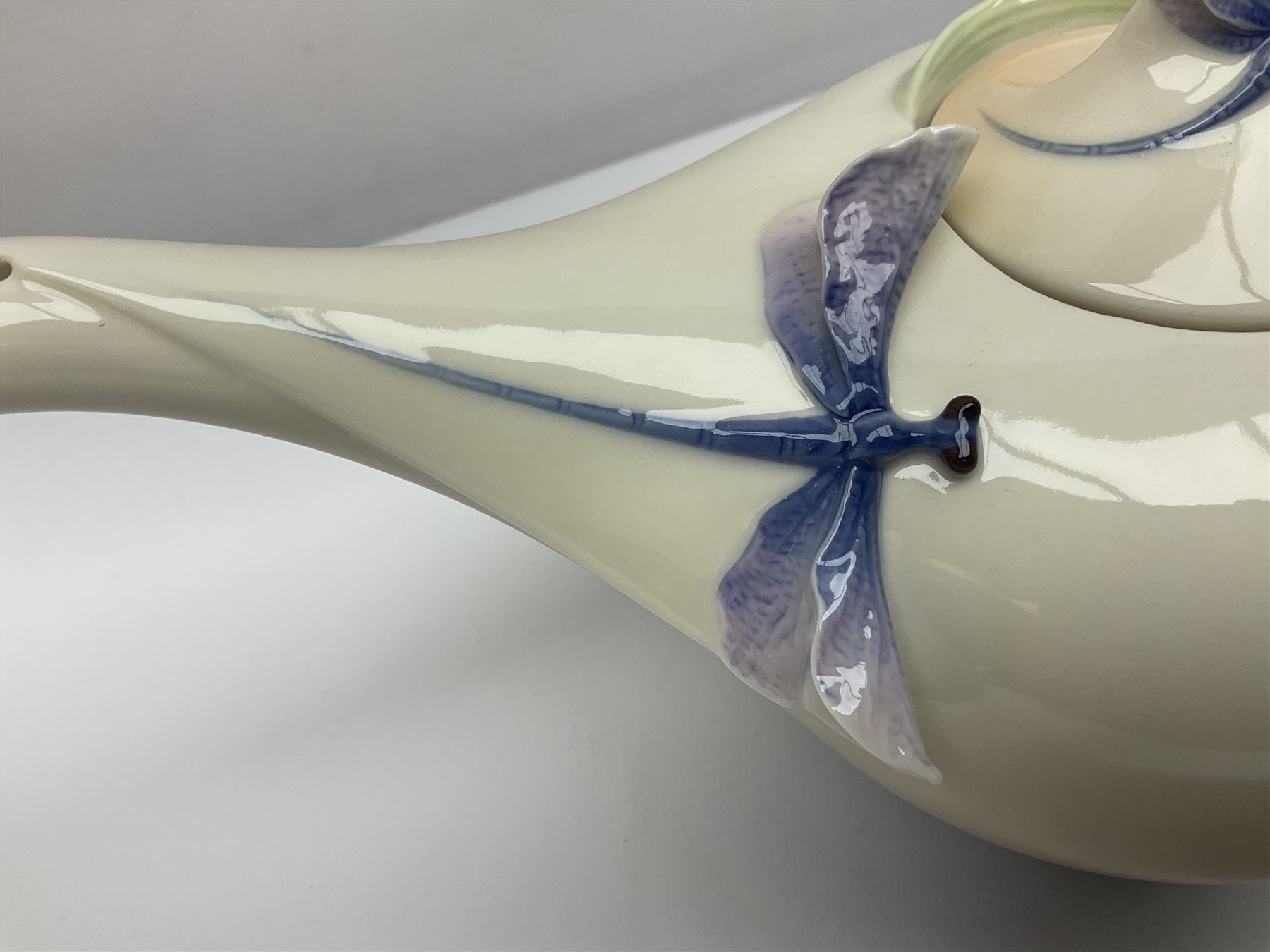 Franz Teapot decorated with dragonflies, together with a matching sucrier and cover and a cup and saucer in Iris pattern, all with printed mark beneath 