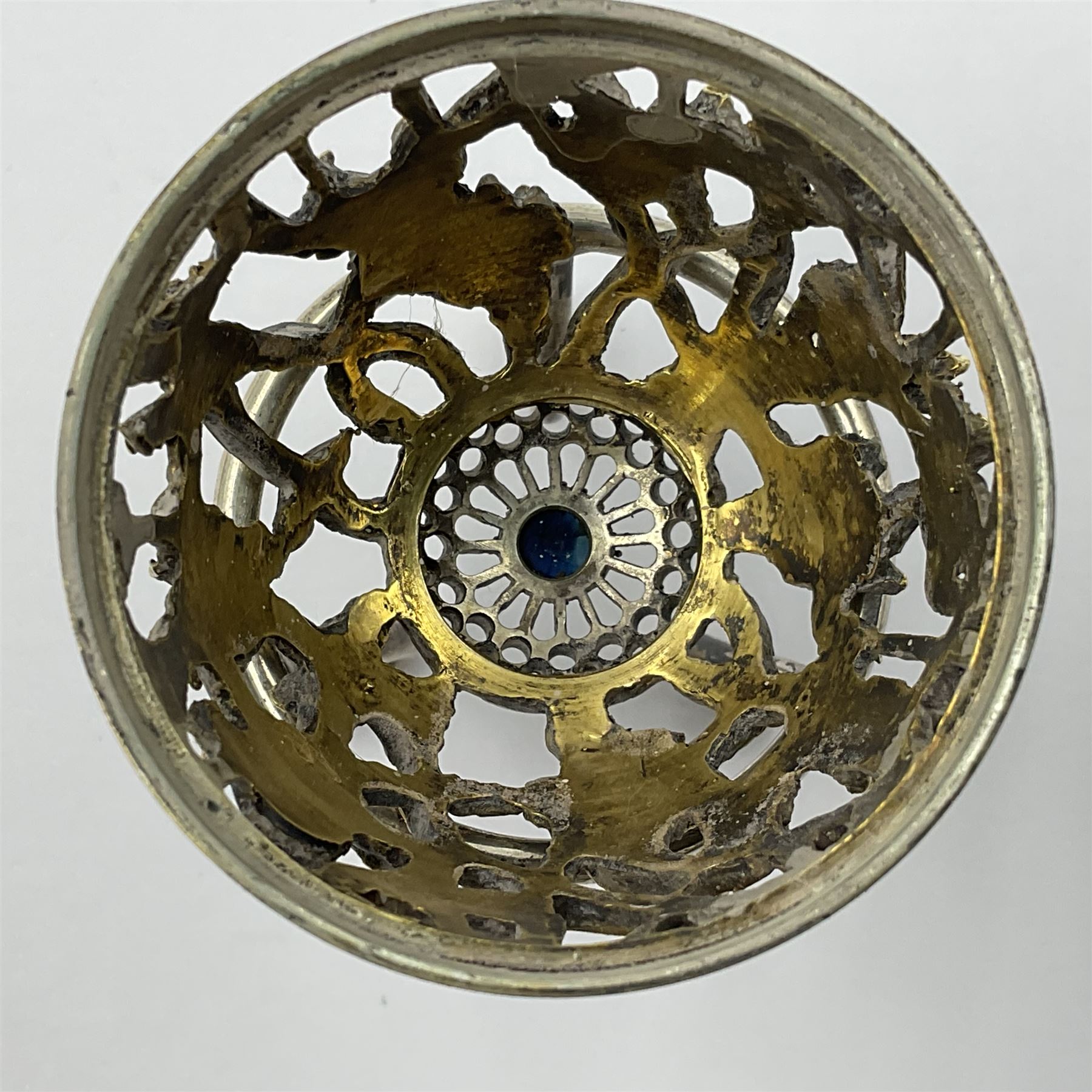 Modern silver limited edition Easter egg, no. 70/500, the gilt openwork body decorated with daffodils and detachable cover with pierced circular panel set with a single faceted blue stone, opening to reveal a gilt interior, upon silver stand with three scrolling pad feet, each hallmarked St James House Company, London 1980, height including stand 8cm
