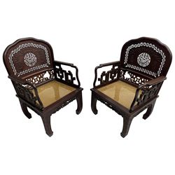 Pair of late 19th century Chinese hardwood armchairs, the pierced and carved back decorated with a central shou motif below a stylised carved bat with a surrounding pierced roundel band, over a cane seat, the apron carved with dragons flanking a floral symbol, the inward swept supports decorated with scrolling foliage