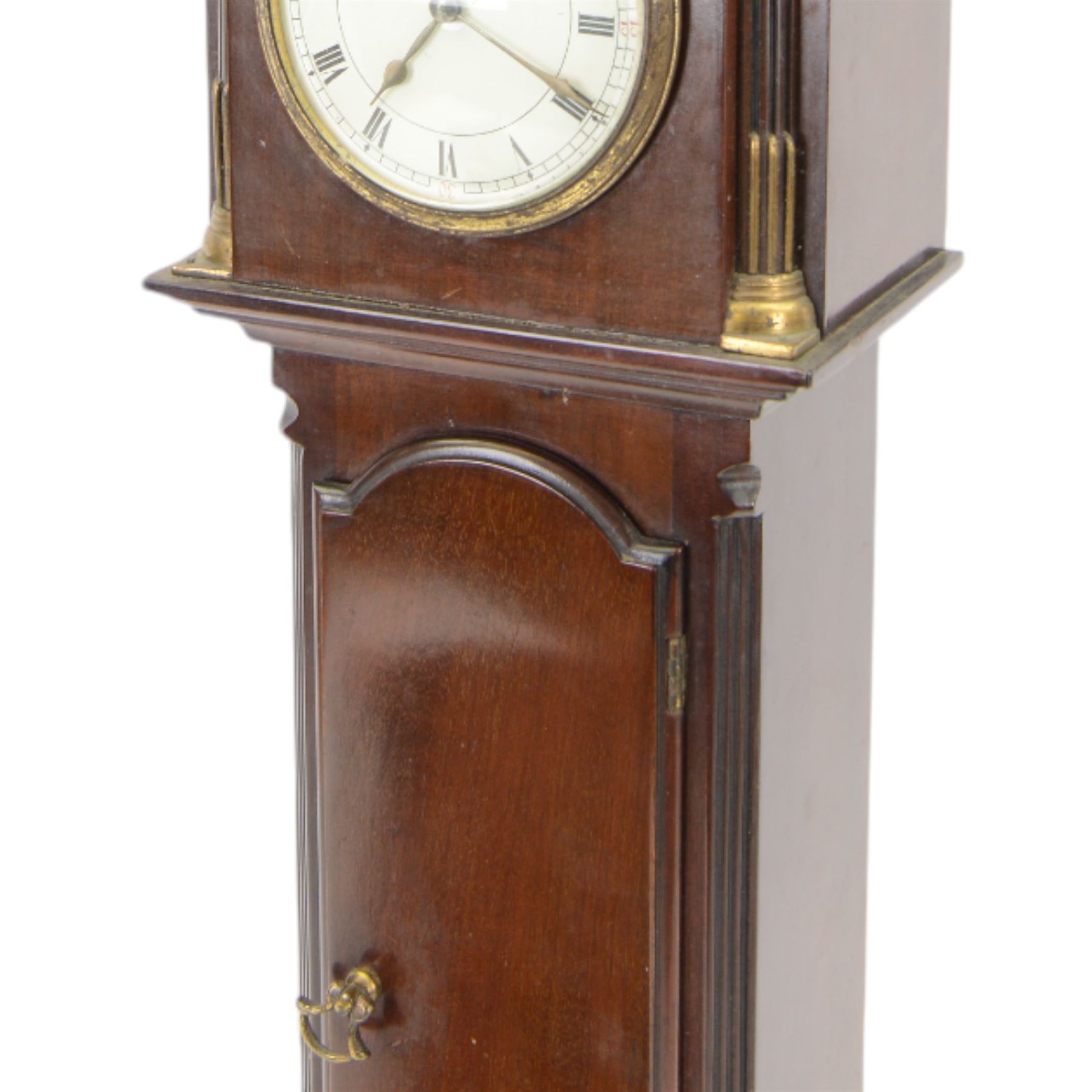 Early 20th century - mahogany cased 8-day miniature longcase clock with a matching wall mounted bracket,  break arch hood with ball finials and recessed quarter pilasters, conforming trunk with a long door and break arch top on a decorative plinth with a raised panel and stepped base, circular dial with Roman numerals and spade hands within a glazed bezel, French insert timepiece movement with a cylinder platform escapement, wound and set from the rear. With key.