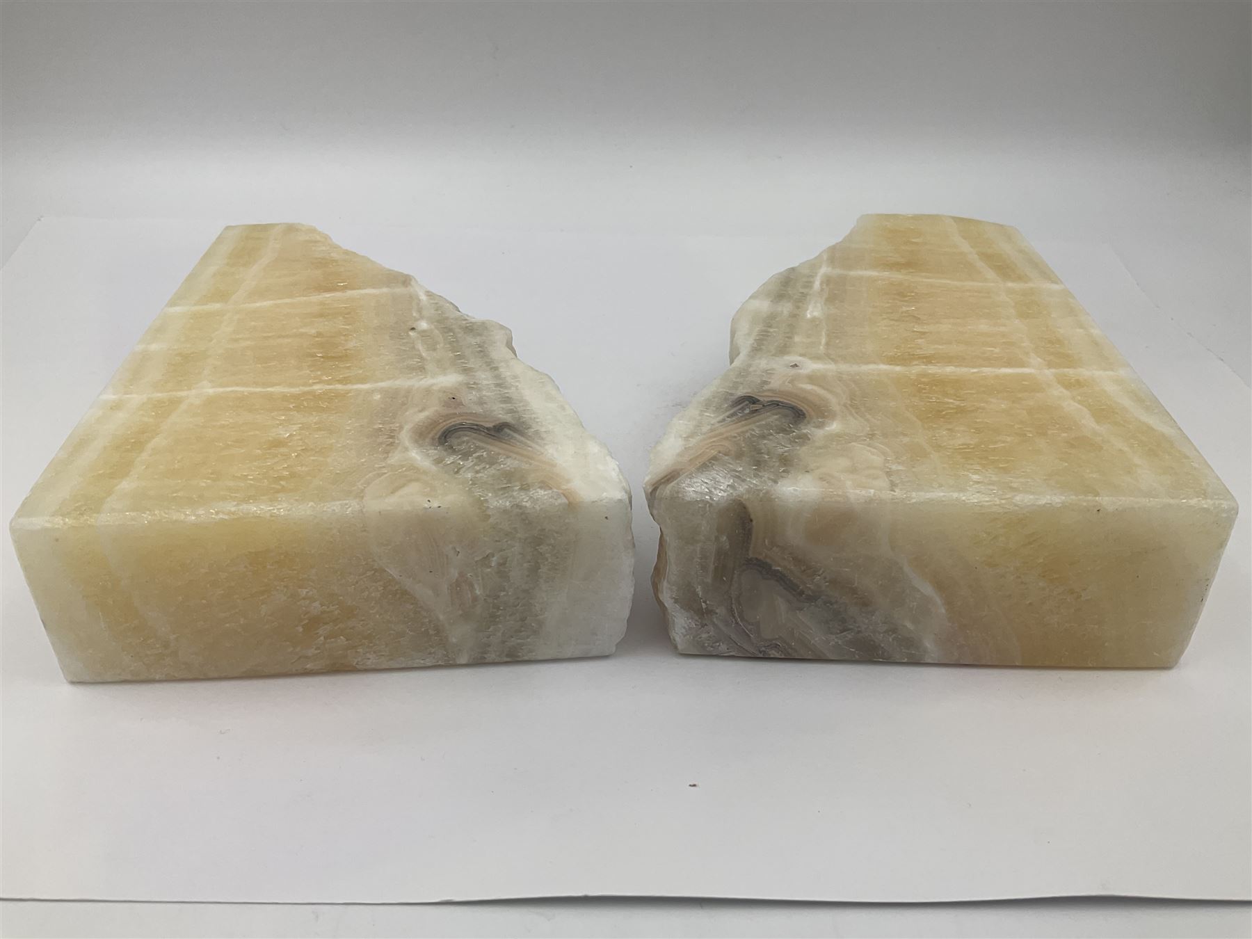 Pair of honey onyx bookends of rectangular form with polished to three sides with a raw outer edge, H18cm 