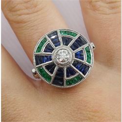Platinum diamond sapphire and emerald target ring, the central round diamond surrounded by calibre cut sapphire and emeralds, with diamond set shoulders