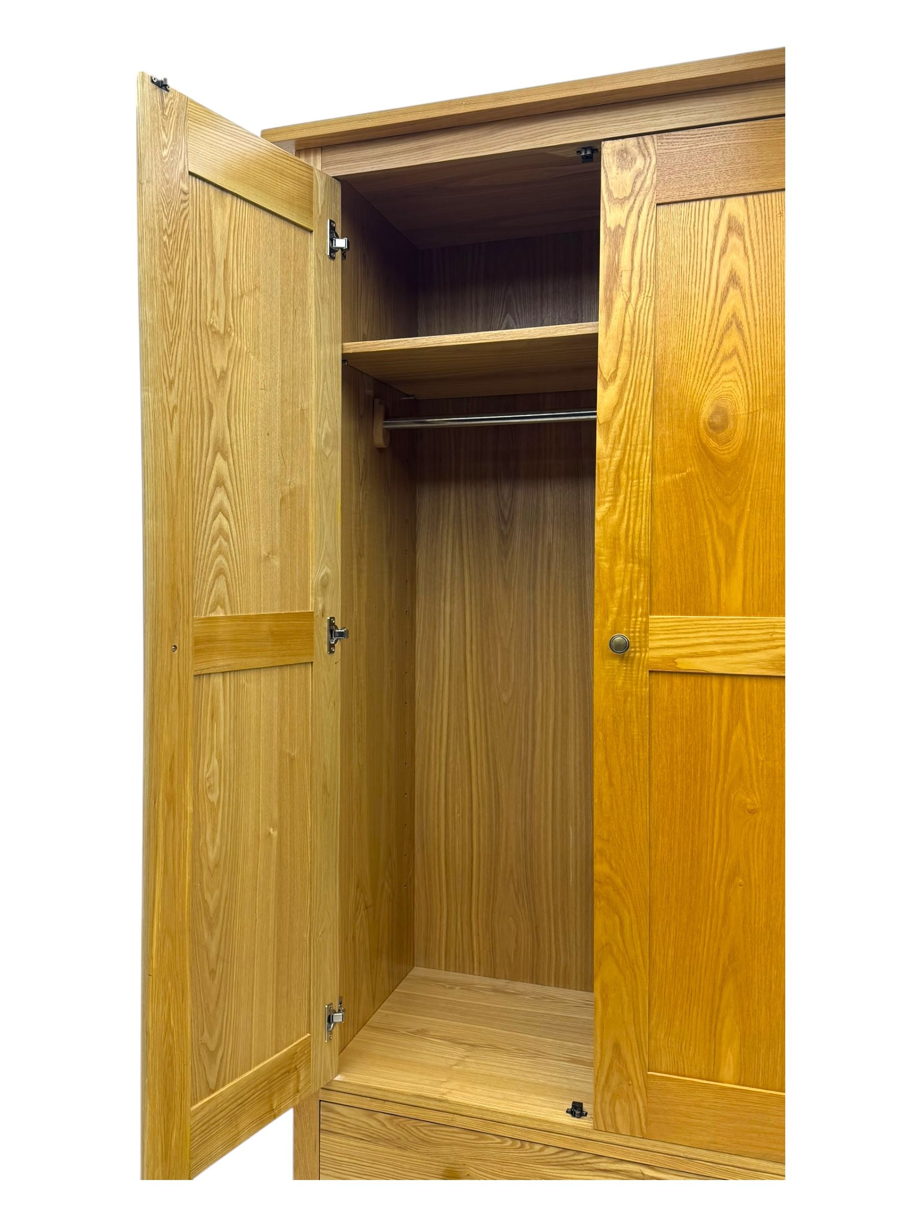 Contemporary light oak double wardrobe, projecting cornice over two panelled doors enclosing hanging rail and shelf, above full-width drawer, on shaped stile supports