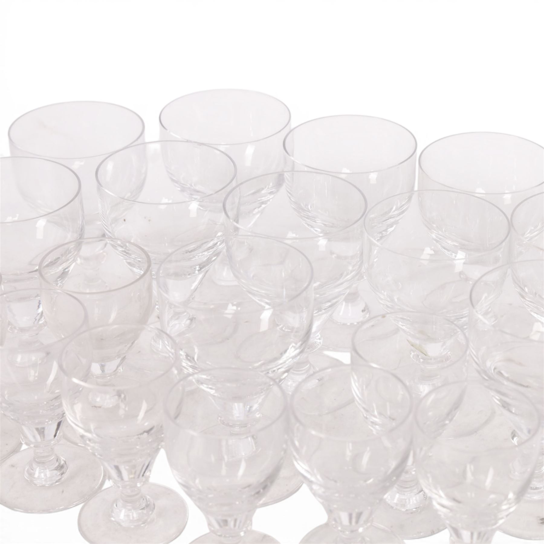 Georgian shaped drinking glasses, comprising eleven larger, H12.5cm, and eight smaller, H10.5cm, each with ovoid bowl upon knopped stem and circular foot