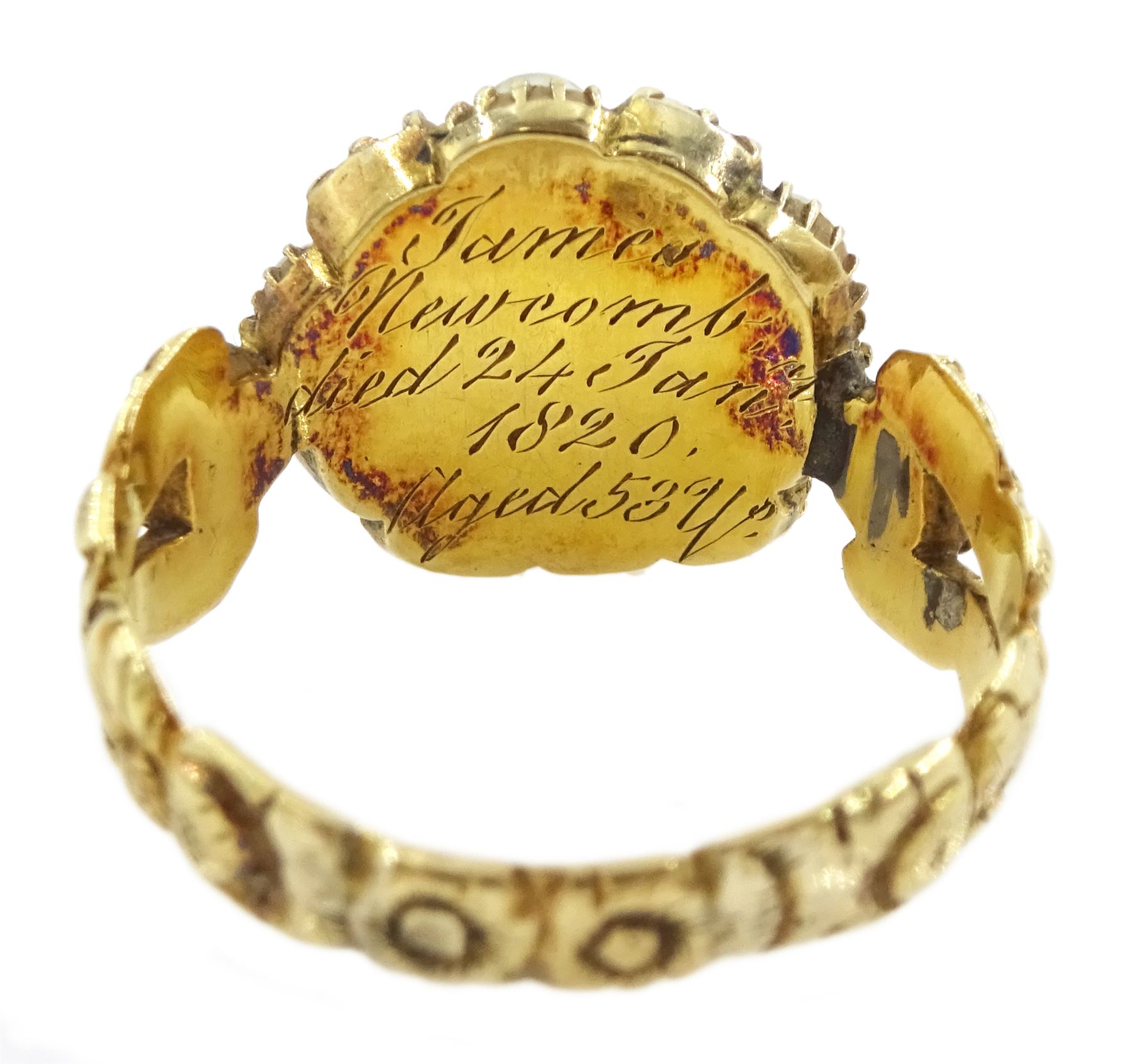 Georgian gold emerald and pearl mourning ring, the glazed central panel containing locket of hair, with emerald and split pearl surround, the shoulders and shank with foliate decoration, the underside of the head inscribed 'James Newcomb died 24 Jan 1820 aged 53 ys'