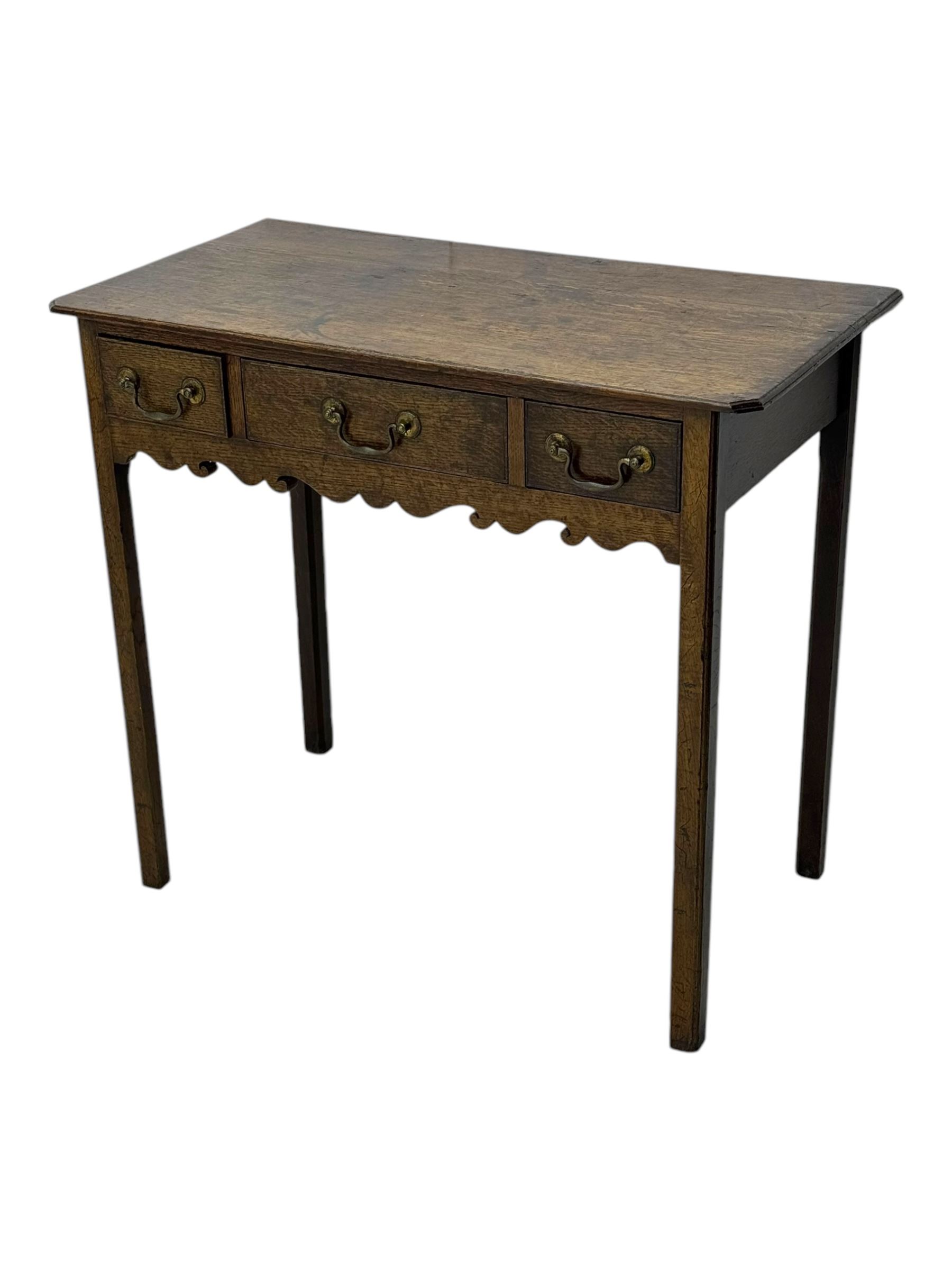 18th century oak lowboy, rectangular moulded top over three frieze drawers with brass swing handles, scalloped apron, on slender square section supports