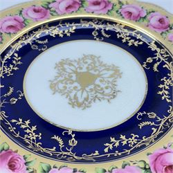 Early 19th century Coalport three handled goblet vase, shape no 114, and pair of plates, each hand painted with flowering pink roses upon a gilt band, against a dark blue ground heightened with trailing gilt tendrils, each marks beneath Coalport Swansea Period 1818, including handles vase H22.5cm, plates D23cm