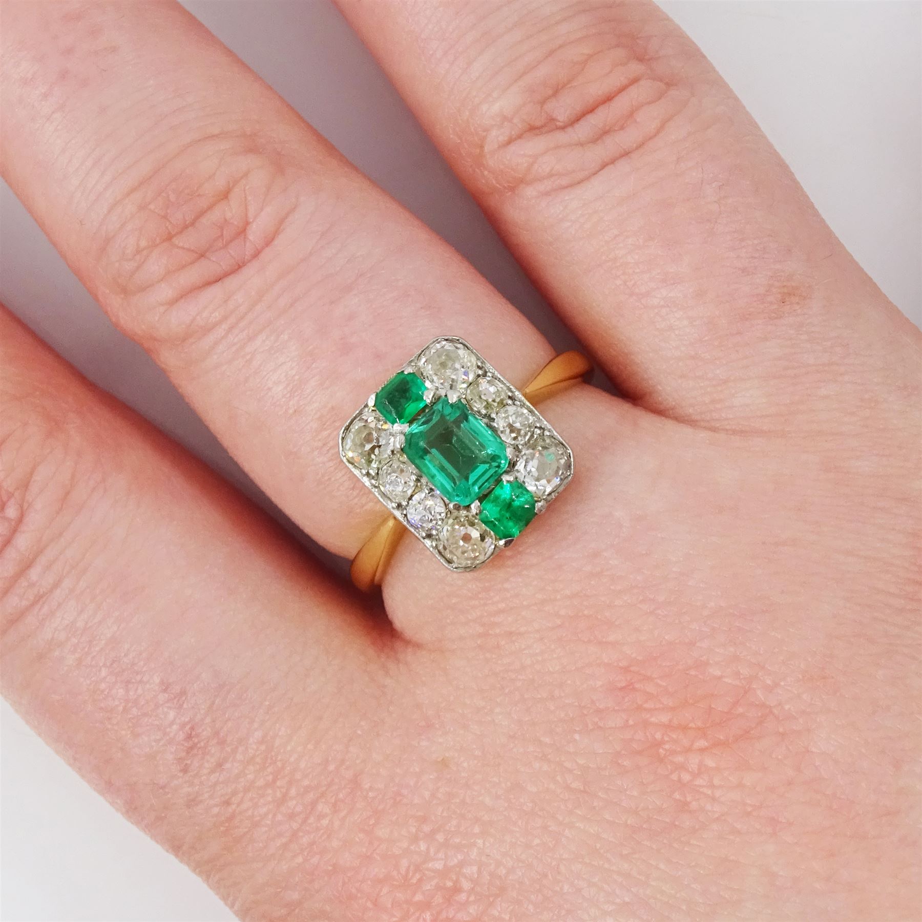 Early 20th century gold emerald and diamond panel ring, three octagonal cut emeralds, with four old cut diamonds set either side, stamped 18ct Plat, total diamond weight approx 0.85 carat
