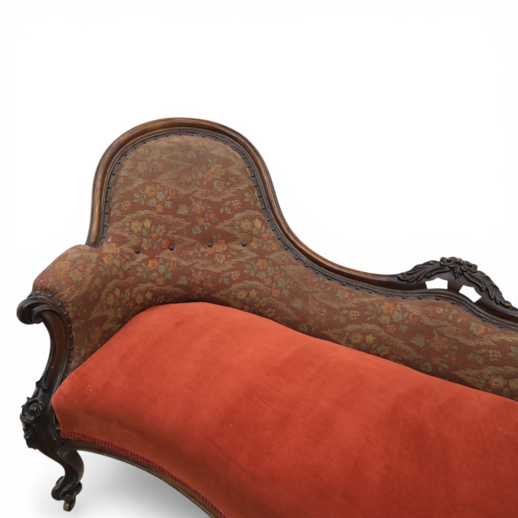 Victorian mahogany framed serpentine sofa, the shaped button upholstered back with central carved foliate cartouche, and scroll arms with carved terminals, over upholstered red seat, upon carved cabriole supports with castors