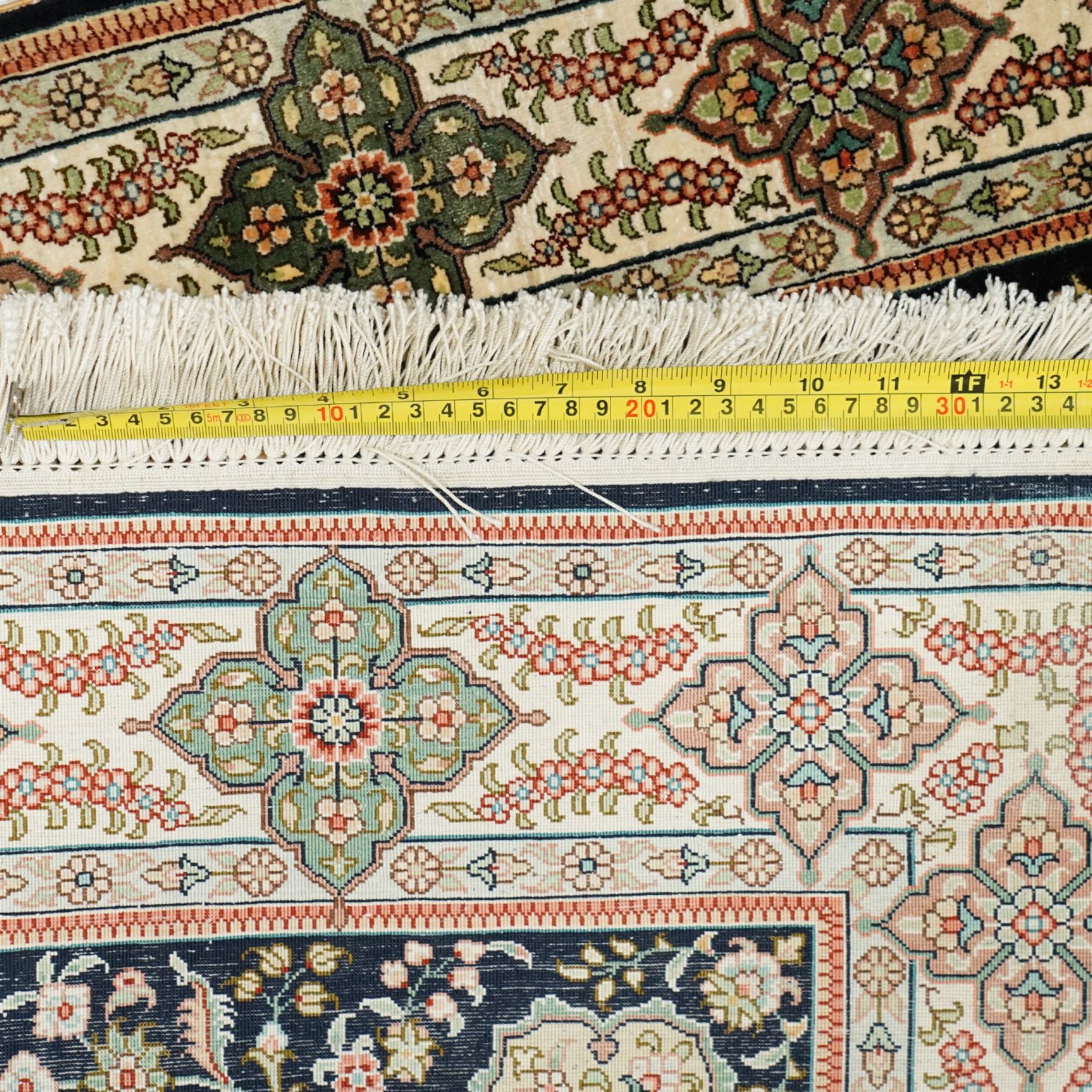 Persian-inspired Qom-style silk rug, deep indigo ground, profusely decorated with foliate motifs and a central medallion, with cotton fringe ends 