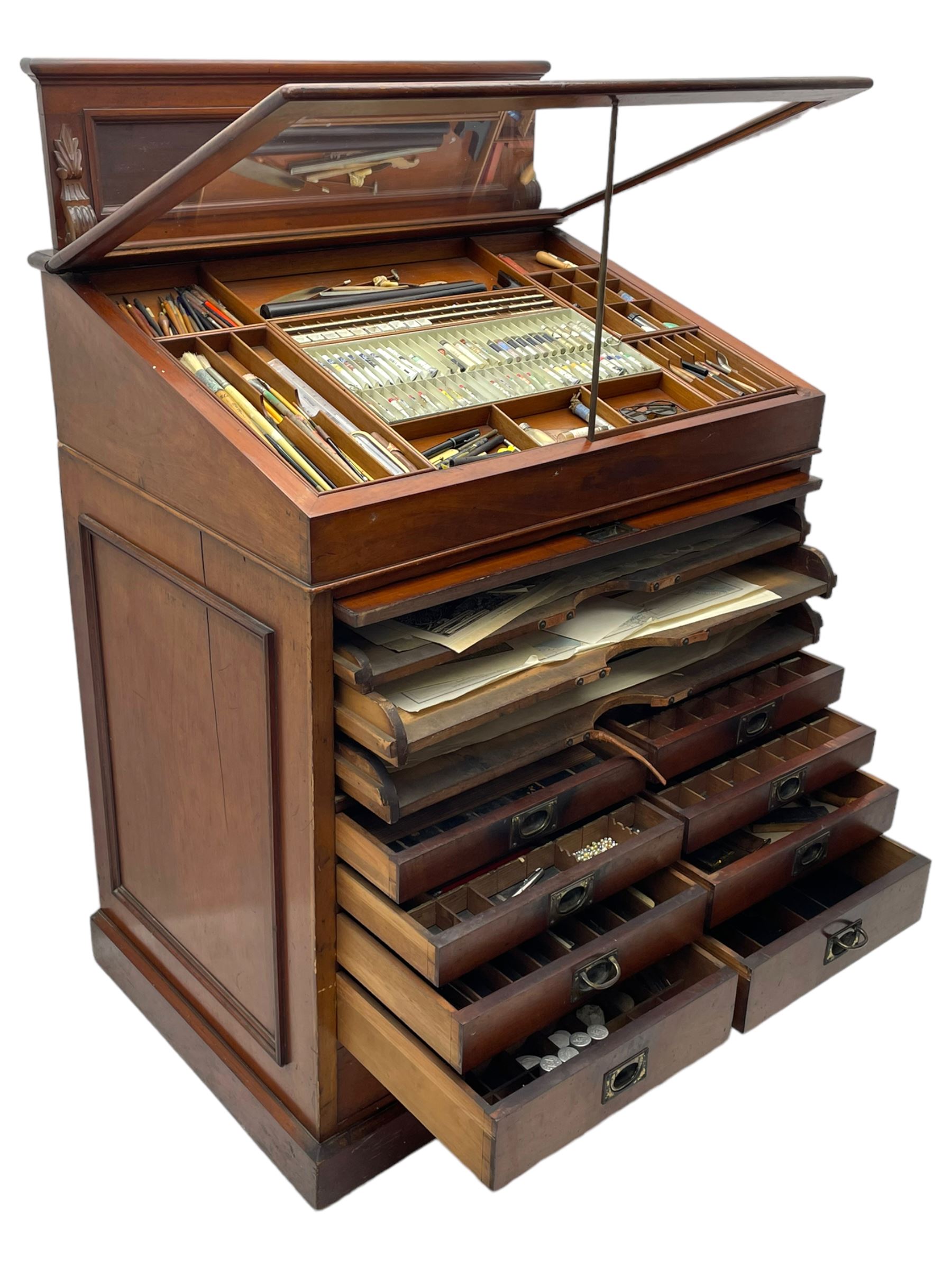Edwardian mahogany artist's cabinet once belonging to the British artist Eli Marsden Wilson (1877-1965), raised panelled back mounted by carved brackets, sloped and hinged glazed lid enclosing paint holders and compartments, up-and-over panelled door revealing three slides, fitted with two banks of five graduating drawers with recessed brass handles, on skirted base.

Together with a quantity of artists' equipment and tools including paints, paintbrushes, charcoal, chalks, etc. and various prints relating to the life of the artist, including Quaker anti-war posters, Victorian Stevengraphs, and various chromolithographs 

Provenance: Removed from the studio of Eli Marsden Wilson. The cabinet comes to us for sale through family descent. The vendor is descendant of Marsden. Many further etchings removed from the cabinet are being sold in the Spring Art Sale, Friday 15th March 2024, Lots 265-271.

Notes: born in Ossett, Eli Marsden Wilson was the only son of Alfred Wilson, a foreman beamer, and Emma Marsden, and had five sisters. After studying at Wakefield College of Art, he moved to the Royal College of Art in London, where he became a pupil of Sir Frank Short. He had his first exhibit at the Royal Academy in 1905, the same year he married fellow artist Hilda Mary Pemberton.

A Quaker, vegetarian, and pacifist, he was a conscientious objector in World War I and as such was imprisoned in 1917 for two years. In September 1922 he was commissioned by Princess Marie Louise to produce miniature etchings for Queen Mary's Dolls' House at Windsor Castle; two such etchings are being sold in the Spring Art Sale, Friday 15th March 2024, Lot 265.