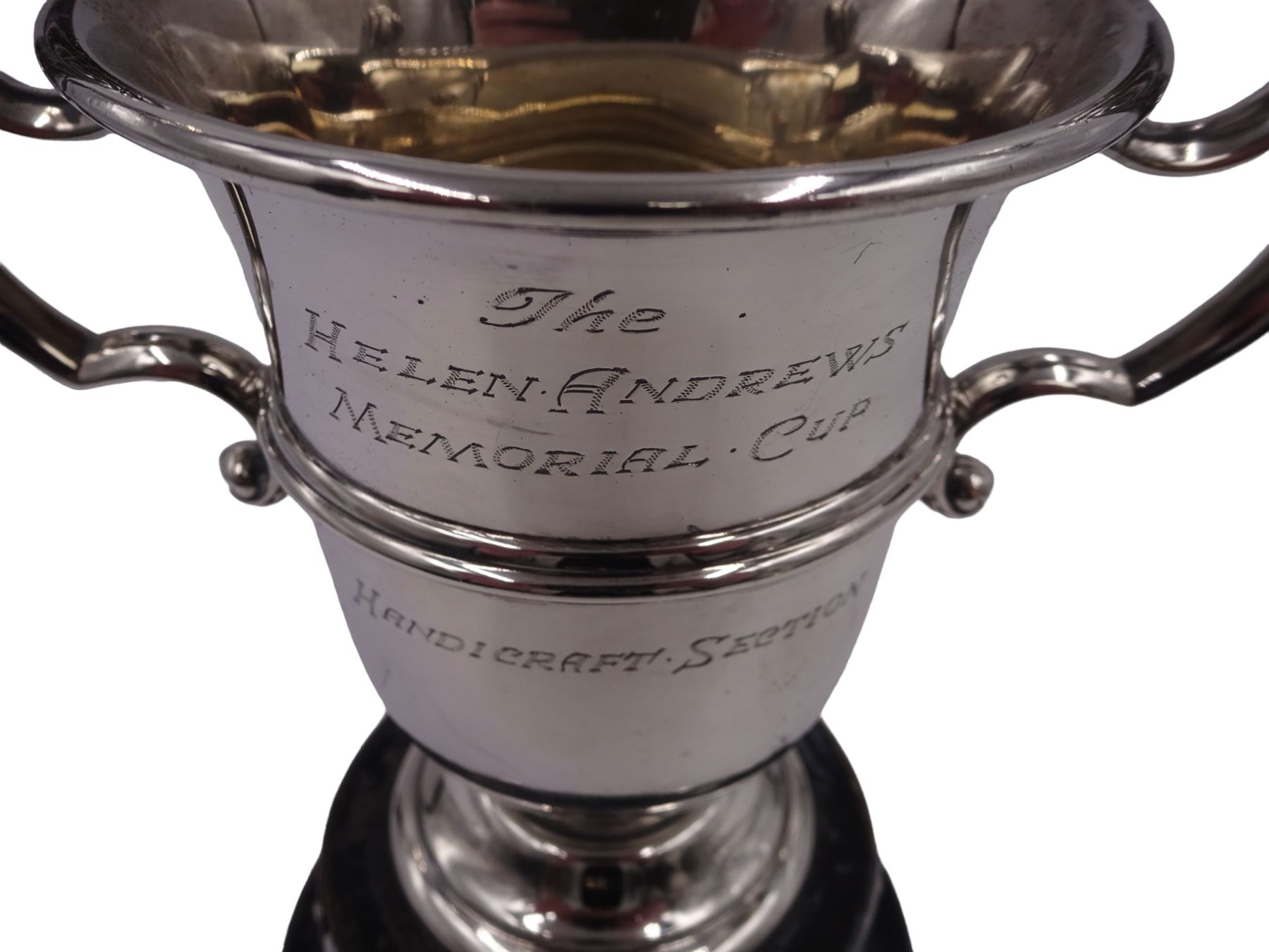 1920s silver trophy cup, with twin scroll handles and girdle, upon circular stepped foot,  the body with presentation engraving 'The Helen Andrews Memorial Cup, Handicraft Section', hallmarked Walker & Hall 1927, fixed upon ebonised wooden base with applied winners plaques, including base H18cm