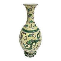 20th century Chinese Famille Verte vase, of slender ovoid form with tapering neck and flared rim, decorated with green and grey enamel with dragons chasing flaming pearls amongst auspicious clouds upon a yellow ground, H30cm