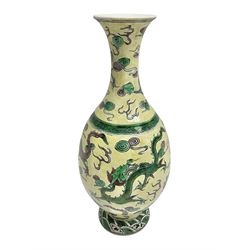  20th century Chinese Famille Verte vase, of slender ovoid form with tapering neck and flared rim, decorated with green and grey enamel with dragons chasing flaming pearls amongst auspicious clouds upon a yellow ground, H30cm