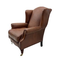 Laura Ashley - wingback armchair, upholstered in brown leather, on turned and fluted supports with brass castors