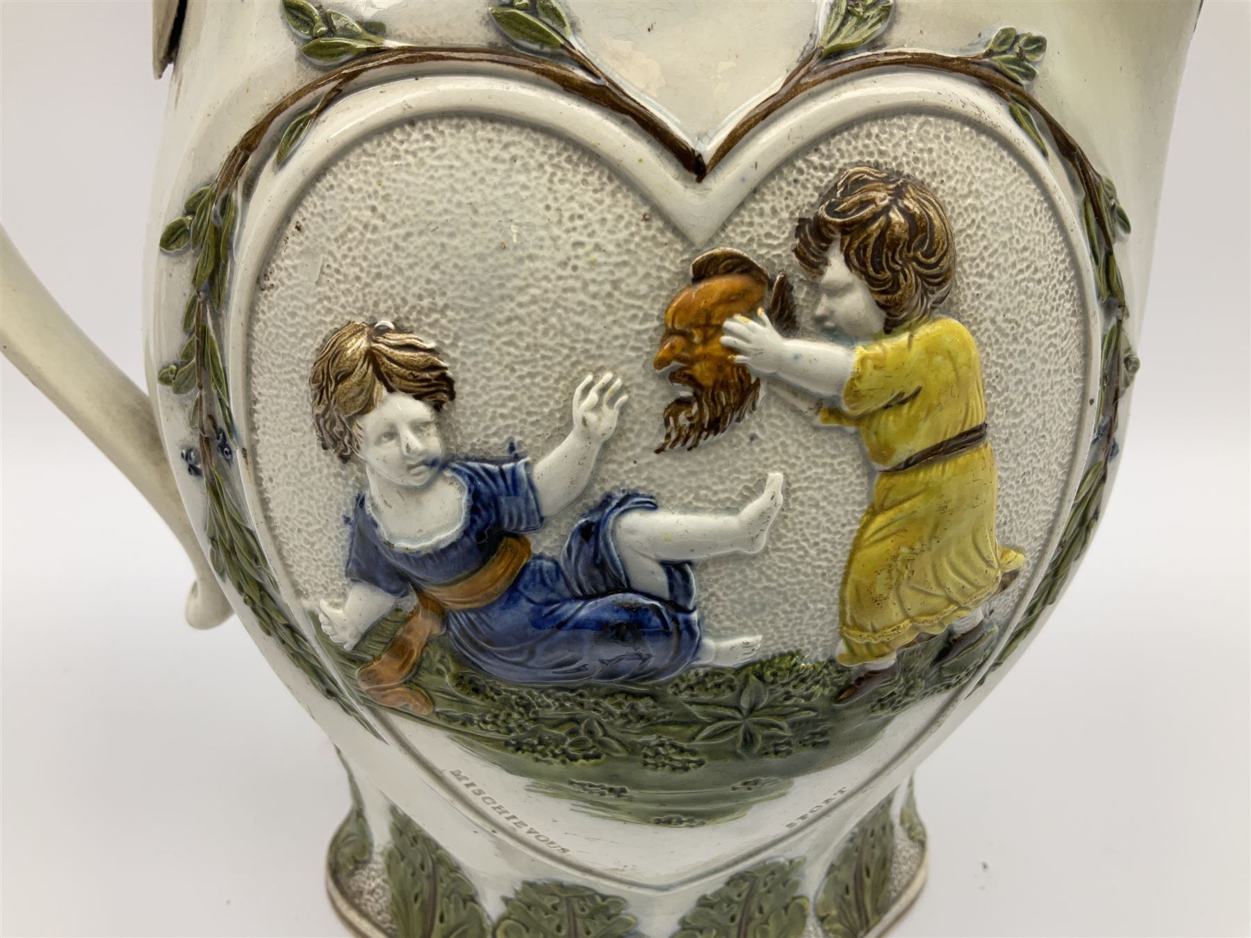 Early 19th century Prattware jug, circa 1800, decorated with two heart shaped panels of children, titled Sportive Innocence and Mischievous Sport, further decorated with acanthus and foliate borders, H22cm