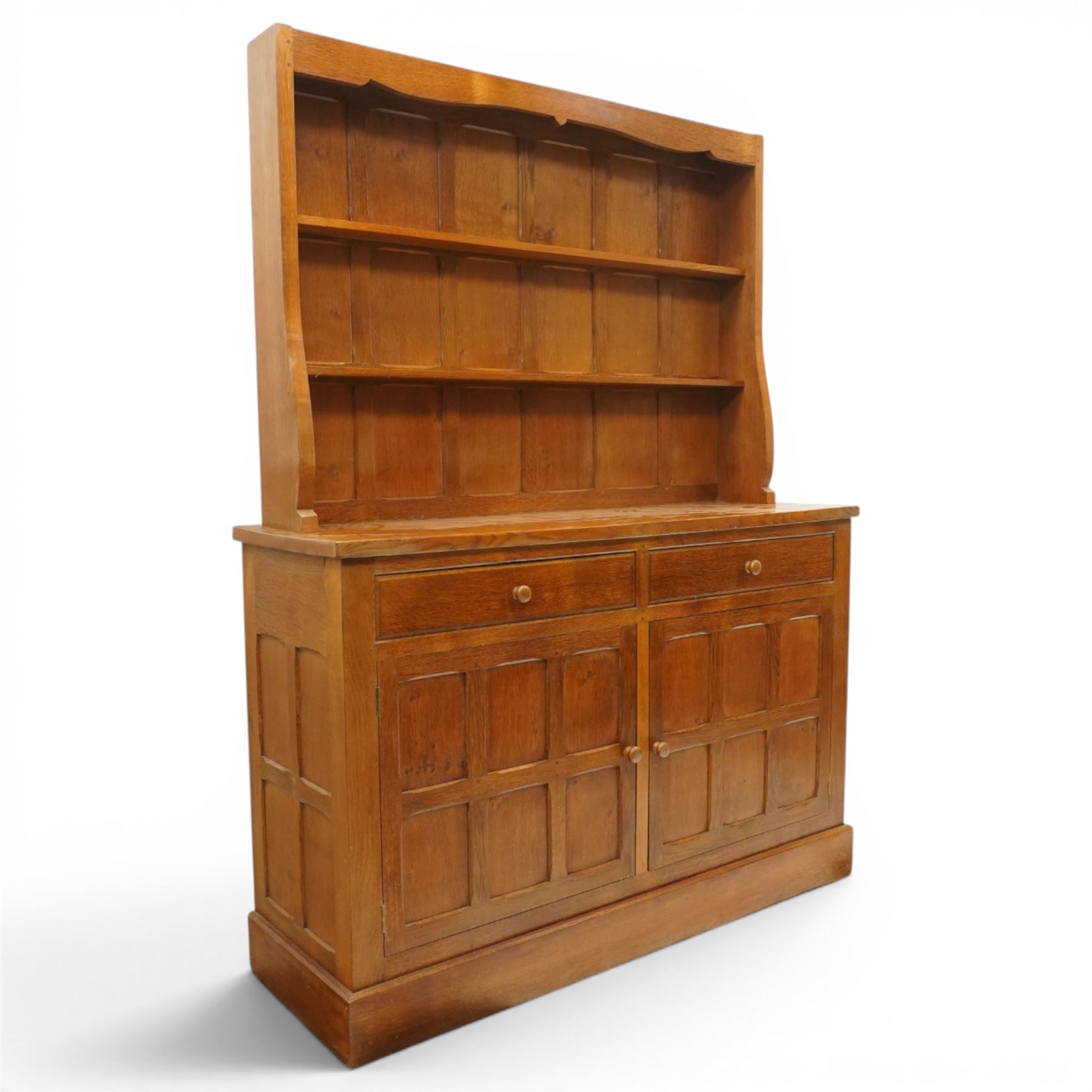 Cat and Mouseman - adzed oak dresser and plate rack, plate rack with two delf rack, panelled back and shaped uprights, above a base with two short drawers and turned wooden handles, panelled cupboard doors and sides, raised on a plinth base, with carved Cat and Mouseman signature, by Lyndon Hammell of Harmby