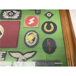 Framed display of thirty-four WWII German cloth badges including Luftwaffe pilot, Paratrooper, Afrikakorps cuff title, sleeve insignia for 'SS' Foreign Volunteers, various breast eagles including Luftwaffe, Army etc, RAD badges, Party Armband, rank and trade insignia, cap insignia etc; 40 x 50cm in modern pine frame
