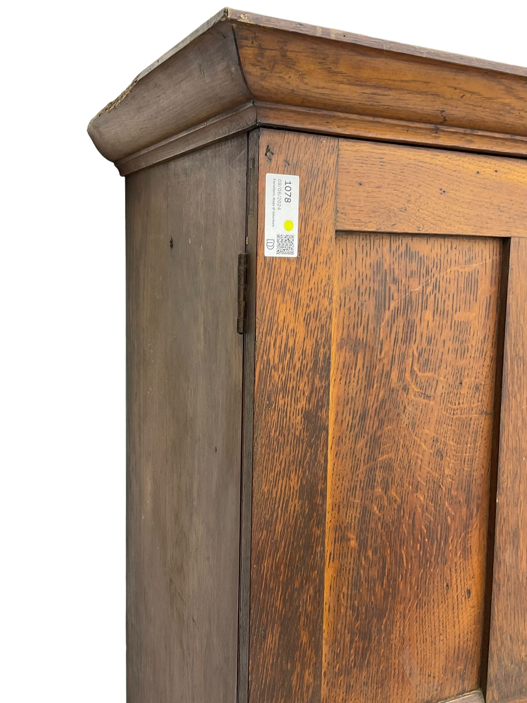 The North of England School Furnishing Company Limited Darlington - early 20th century oak school cupboard, projecting moulded cornice over two panelled doors, fitted with shelves, on chamfered plinth base 