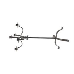 Wrought hand forged iron candle stand, four scrolled branches and central vertical branch with sconces, tapered column on four shaped and out splayed supports